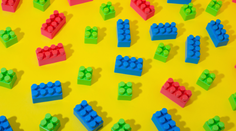 Scattered pieces of colorful Lego on a yellow background
